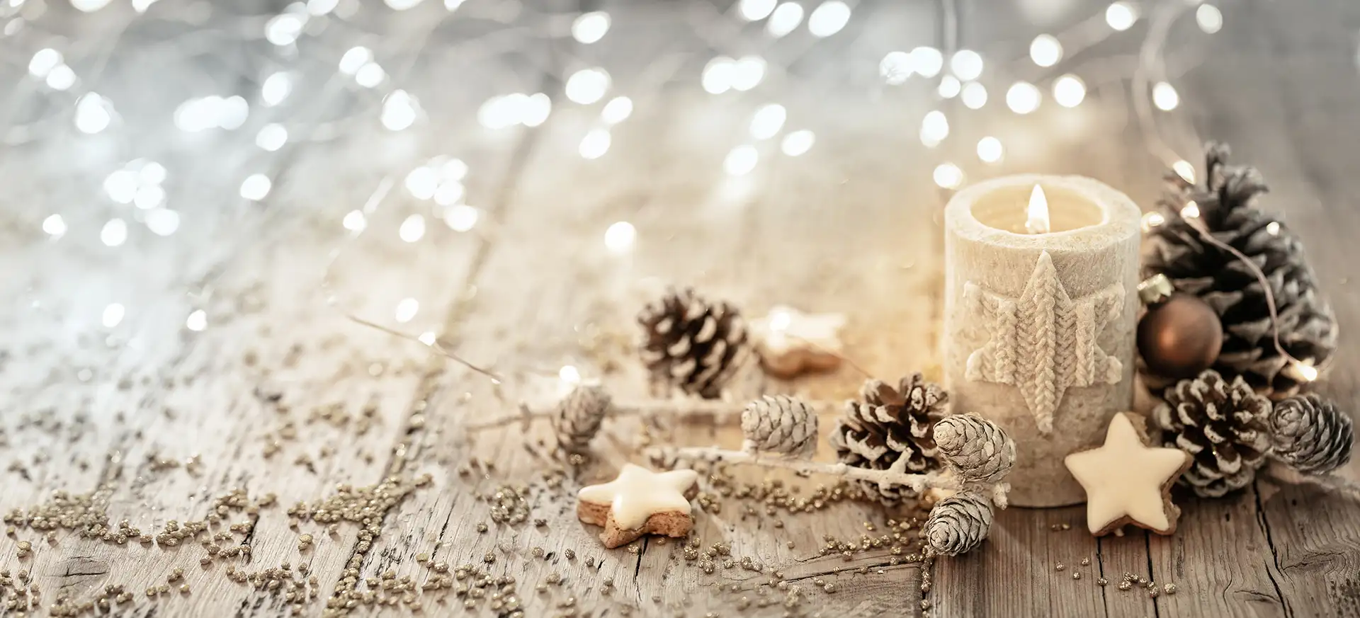 Weihnachtliches Bild mit einer brennenden Kerze, Tannenzapfen, Sterne und Kugeln