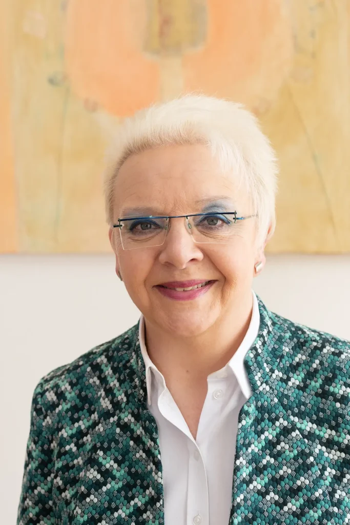 Frau mit Brille und kurzen blonden Haaren lächelt freundlich