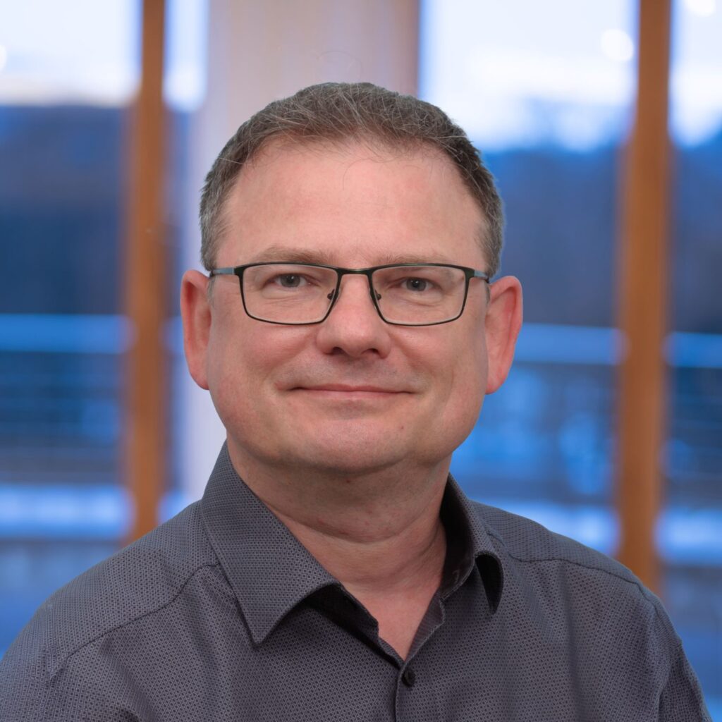 Mann mit Brille lächelt freundlich in die Kamera.