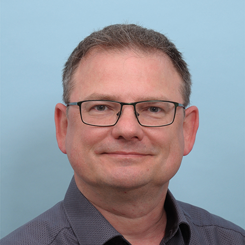 Mann mit Brille lächelt freundlich in die Kamera.