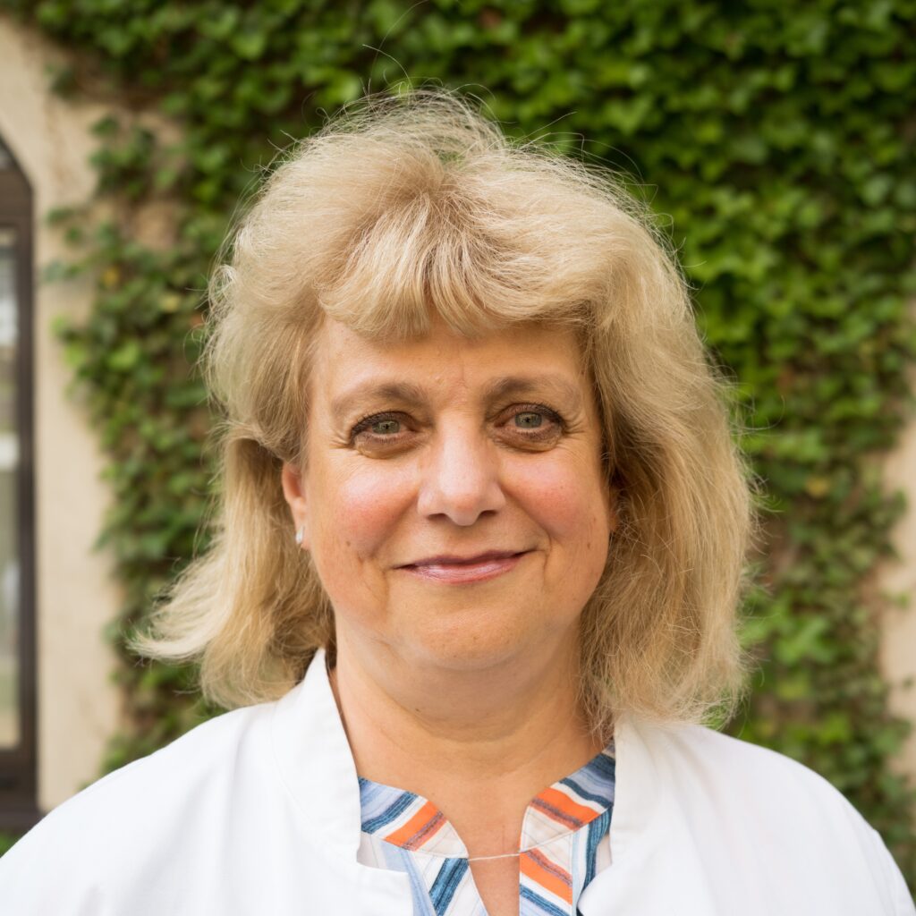 Frau vor grünem Hintergrund lächelt freundlich